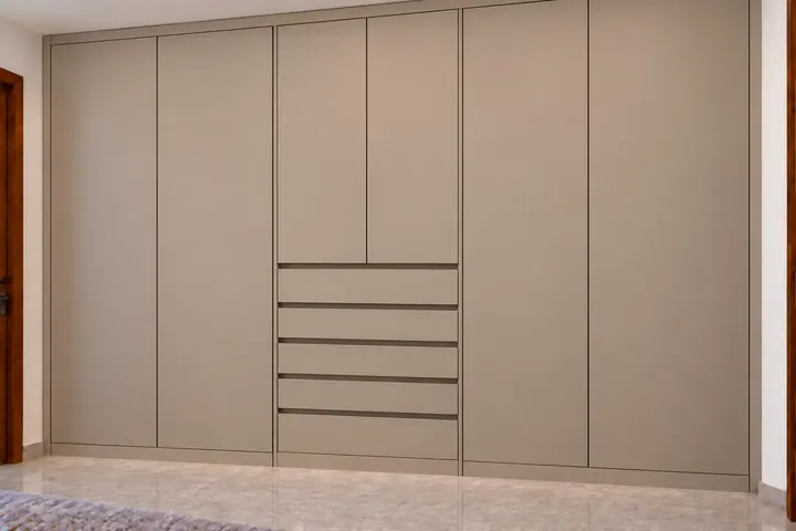 Diseño de closet taupe de piso a techo con puertas lisas y cajonera central