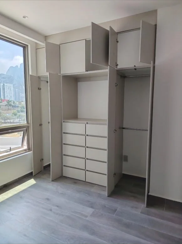 Obra real: closet con cajonera integrada, puertas abiertas y vista a la ciudad