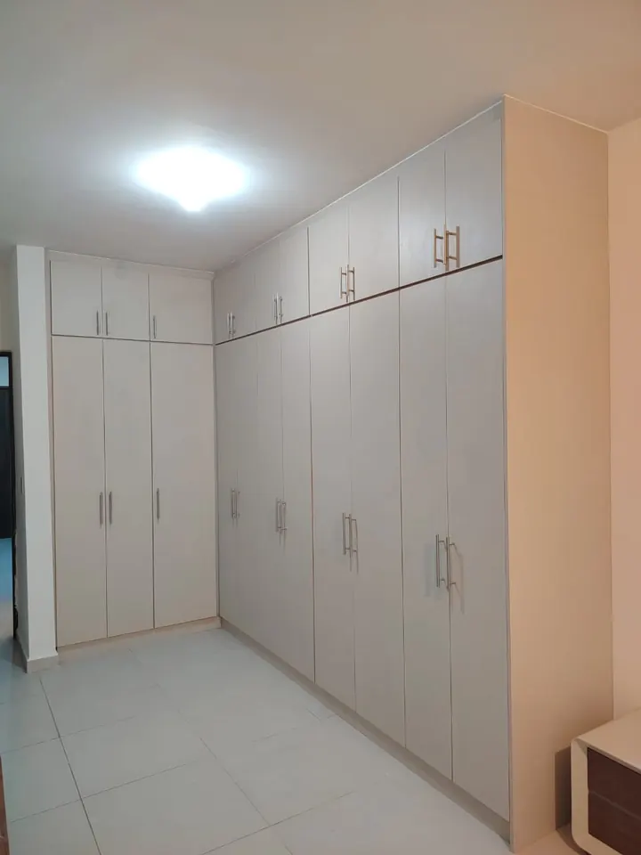 Obra real: closets de piso a techo en tono claro con jaladeras metálicas