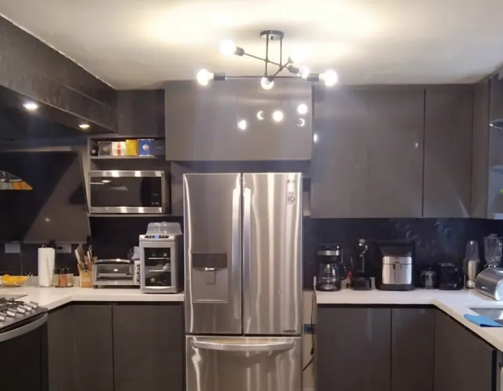 Obra real: cocina en grafito con refrigerador de acero, lámpara tipo candil y piso de mármol